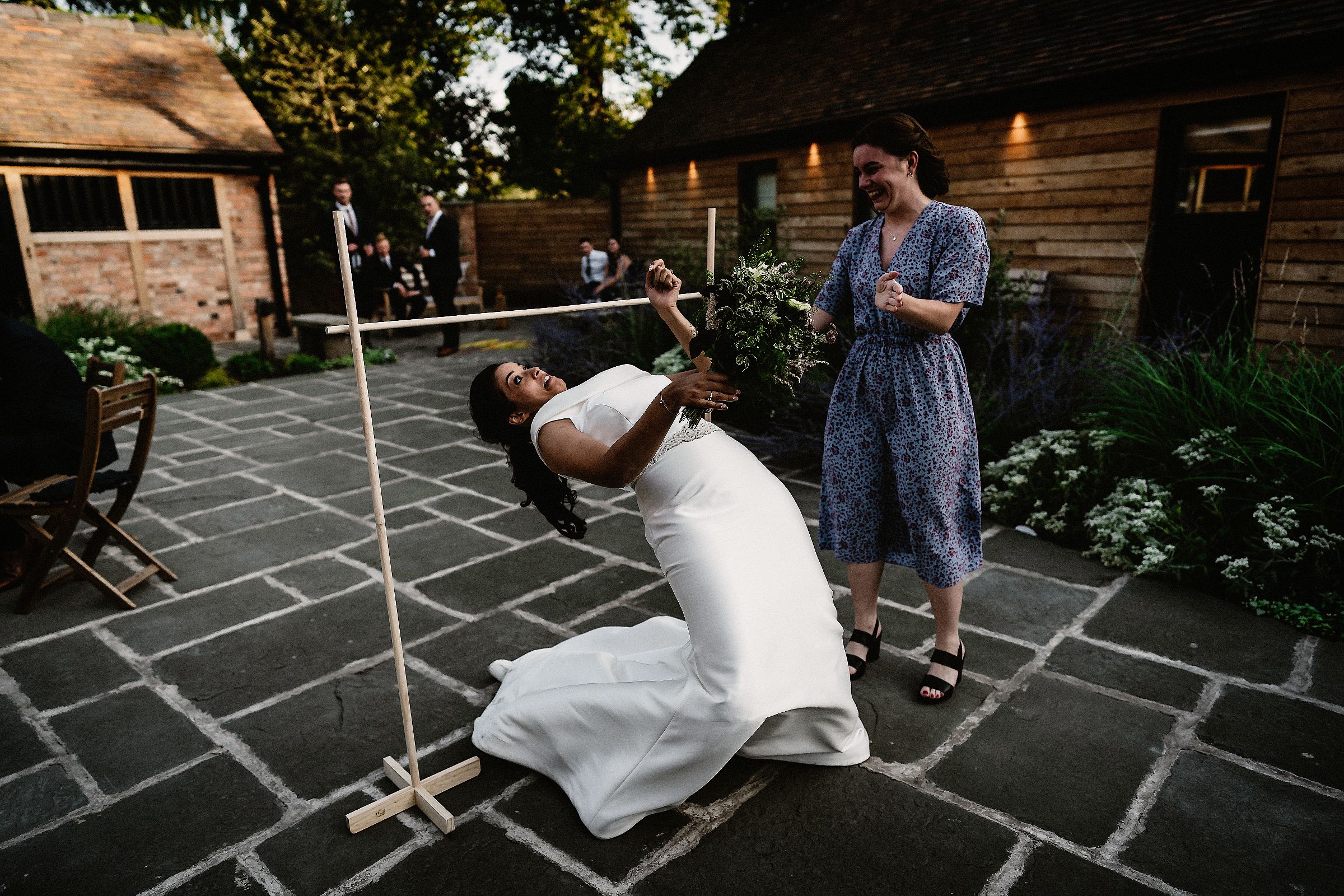 bride doing the limbo on her wedding day at barns and yard